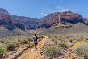 Fototapeta premium A woman is walking on a trail in the desert