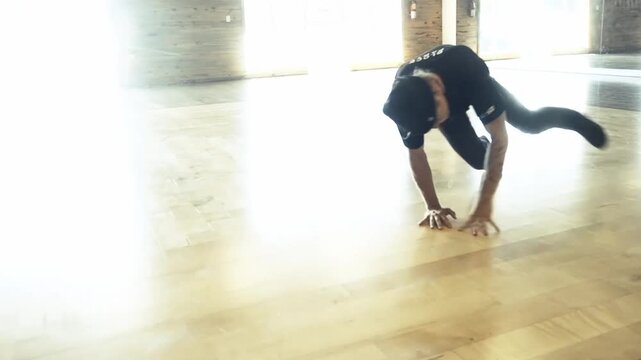 A slow-motion of a Caucasian guy breakdancing in a room