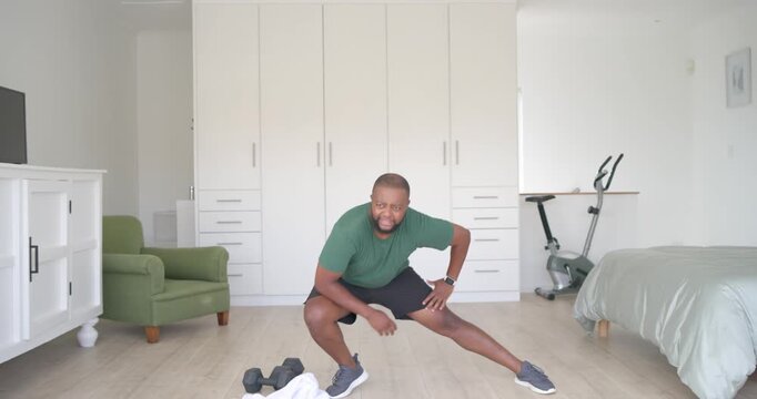 Man starting warmup pulling knee balancing lunging, rotating in bedroom with bike wearing green top