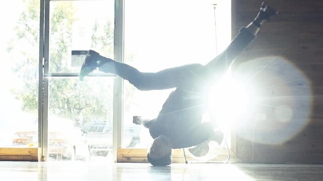A slow-motion of a Caucasian guy breakdancing in a room