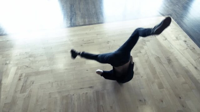 A slow-motion of a Caucasian guy breakdancing in a room