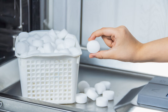 Woman hold a salt pellet in your hand to soften the water for the care of the appliance.