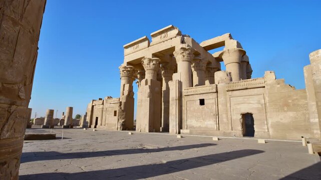 Kom Ombo temple ruins with double columns and composite capitals against clear blue sky in Egypt, ancient Ptolemaic architecture dedicated to Sobek and Horus with damaged walls.