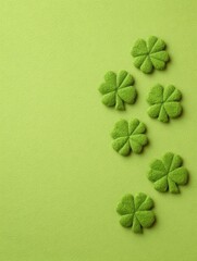 Naklejka premium Green felt four leaf clovers arranged on light green background with copy space on the left.