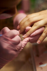 Women's manicure. Female hand undergoing a manicure procedure. The master does a women's manicure. A manicurist files a women's nails in a salon. Hygiene and hand care for woman. manicure design.