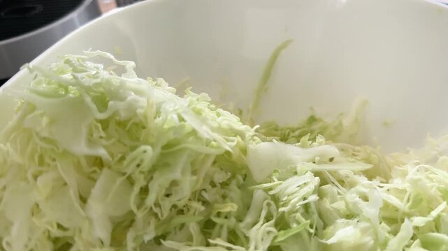 Professional chef person making organic fresh co salad cutting cabbage on a metal mandolin cutter, grater, slow motion