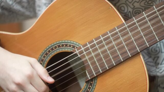 Young boy concentrating on playing a classical acoustic guitar. Practicing music as a hobby and developing a skill