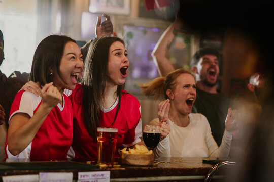 Excited female friends watching sports in a bar