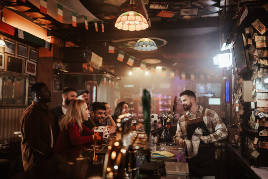 Bartender serving diverse customers at rustic pub gathering