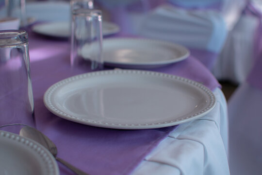 Imagen horizontal de una mesa con platos y vasos limpios estilo banquete 