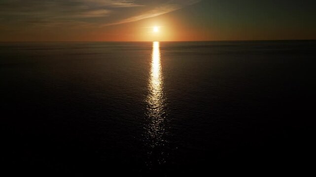 Panoramic aerial view of sunset over the ocean, reversing camera movement.