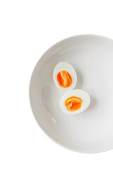 Cooking soft boiled eggs cut in half placed on a white plate ready to be served in a kitchen setting during breakfast time