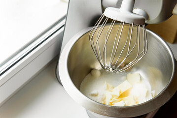Close-up of a stand mixer creaming together butter and sugar for sugar cookie dough, creating fluffy base.