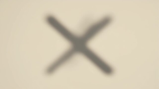 Blurry dark cross symbol on a light beige background