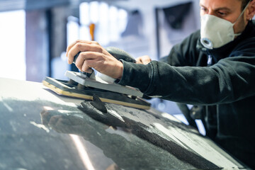 Auto body repairman sanding car surface with protective mask © unai