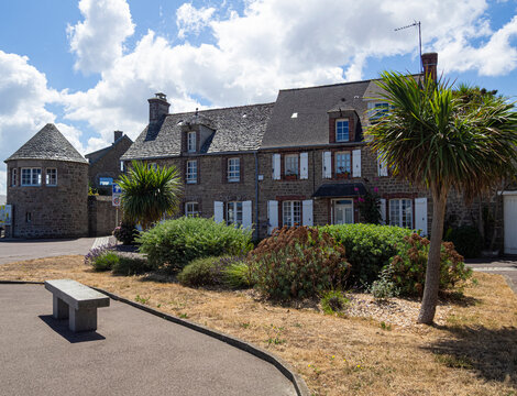 T&iacute;picas construcciones de casas con buhardillas, tejados oscuros y plantas verdes en la calle en el pueblo Barfleur, en la Normand&iacute;a francesa, viajando verano 2022