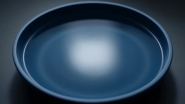 A minimalist, abstract, close-up view of a deep blue plate with smooth, reflective curves and soft lighting
