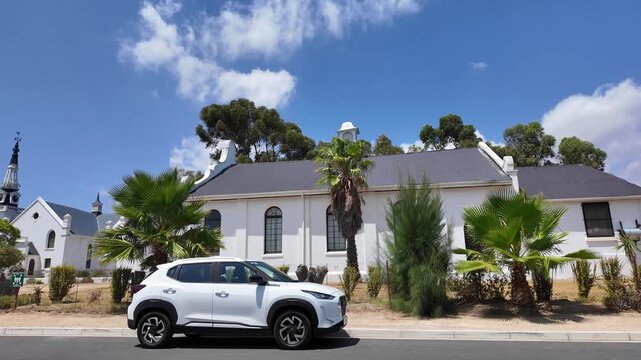 HopefieldSouth Africa. 10.02.2026. A panoramic view of a classic Dutch Reform white church building with a tall spire, surrounded by green trees and a on a sunny day in Hopefield South Africa.