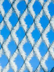 Blue chain link fence white frost crystals pattern geometric texture winter ice detail