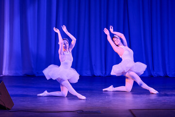 Two ballerinas performing swan lake ballet in white tutus on blue stage © TRAVELARIUM
