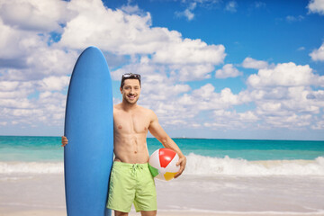 Young man with a surfboard standing at the beach