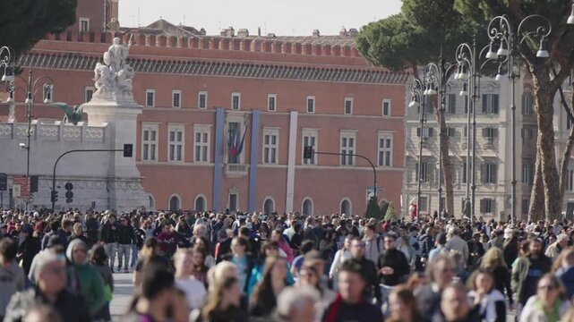 Many people walking on street Via dei Fori Imperiali on sunny day in Rome with view of Alter of Fatherland in background