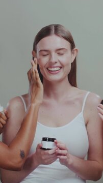 Cream application with joyful teamwork, Smiling beauty experts mutually applying moisturizer in creative setting