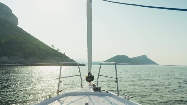 Boat Enters Sunlight. Vessel Glides Into Radiant Water Channel Between Landmasses. Boat Navigates Into Bright And Shimmering Passage Separating Two Islands