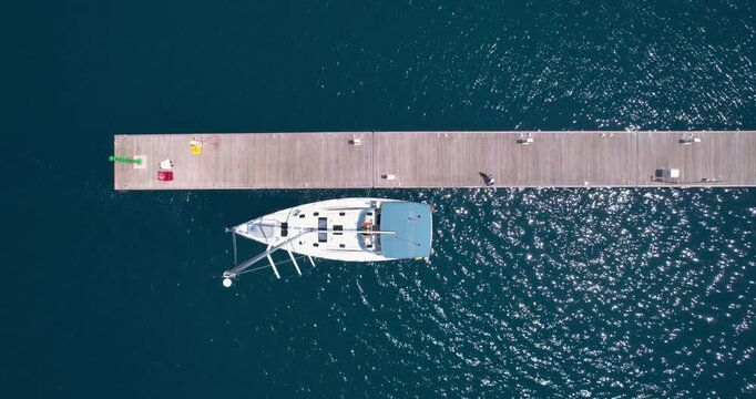 Ship Moored At Dock. Yacht Stationed Alongside Timber Dock With Crew Onboard Present. Luxury Yacht Secured Firmly At Wooden Pier While Crew Members Prepare On Deck