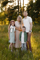 Fototapeta premium Family In Sunlight. Joyful Family In Natural Setting. Caucasian Family Posing In Sunlit Meadow. Family Enjoying Peaceful Moment Together In Sundrenched Meadow During Sunny Day