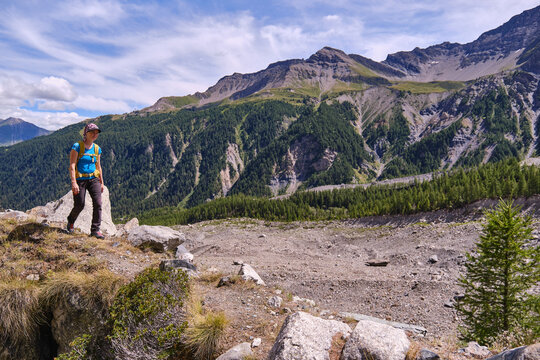 A woman hiker walking along a trail with mountains in the background