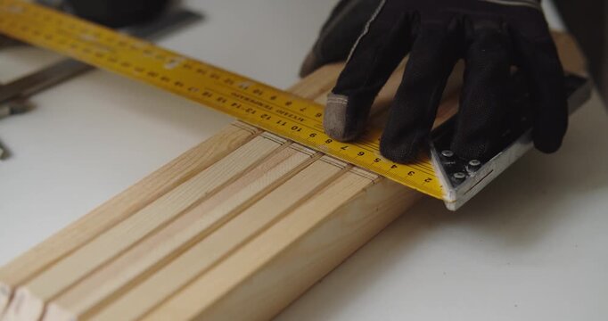 Hands measuring wood with ruler and pencil in workshop setting