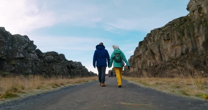 Romantic couple walk visiting Thingvellir national park, Pingvallavatn huge tectonic plates drifting cracks in Iceland, slow motion