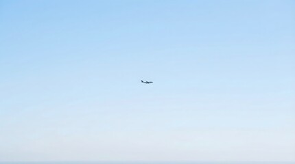 Fototapeta premium A small airplane flies solo in a clear blue sky with soft white clouds.