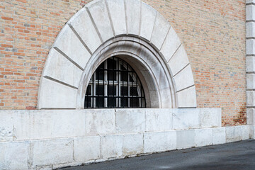Architectural detail of a large arched window embedded in a textured brick wall, showcasing the contrast between natural and man-made materials, ideal for design and renovation concepts.