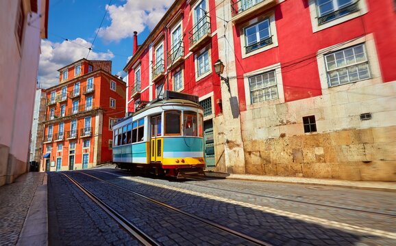 Lisbon, Portugal. Vintage red retro tram on narrow bystreet tramline in Alfama district of old town. Popular touristic attraction of Lisboa city. Public tramways trasport.