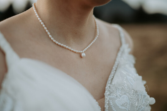 Gros plan sur le collier &eacute;l&eacute;gant et le d&eacute;collet&eacute; d'une mari&eacute;e en robe blanche