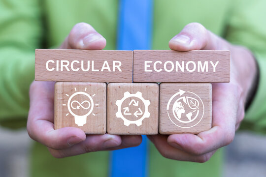 Concept of circular economy. Business person holding wooden blocks with icons sees the text CIRCULAR ECONOMY.