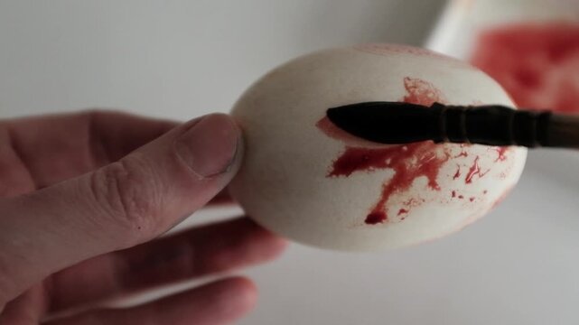 Close-up of the process of dyeing large goose eggs into pastel yellow dye, showing hands coloring Easter eggs for spring holiday decorations and traditional DIY family crafts.