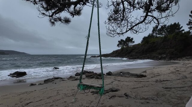 Empty swing swaying on a melancholy beach