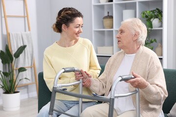 Fototapeta premium Caregiver helping senior woman with walker indoors