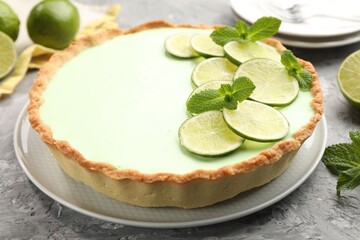 Tasty lime pie with fruit slices and mint leaves on grey textured table, closeup © New Africa