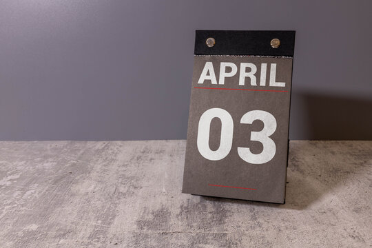 Wooden calendar cubes organizer with date april 3 and hourglass on wooden table.