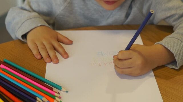 Young left-handed student writing on paper with blue pencil.