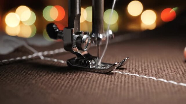 Sewing machine needle stitching white thread on brown fabric.