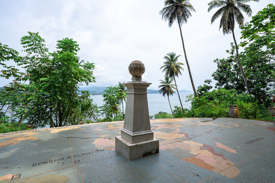 A stone geographic monument topped with a globe standing on a tiled world map at the Equator crossing on Ilh&eacute;u das Rolas, S&atilde;o Tom&eacute; and Pr&iacute;ncipe.