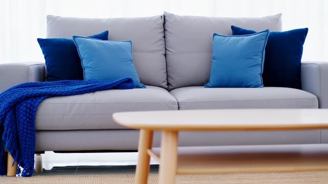 Light gray couch with blue throw and pillows, wooden coffee table