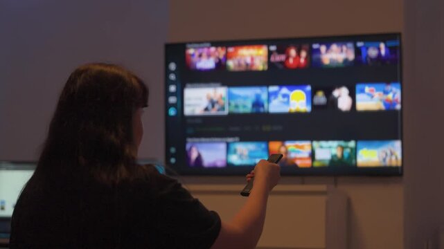 Woman browsing streaming apps on smart tv with remote