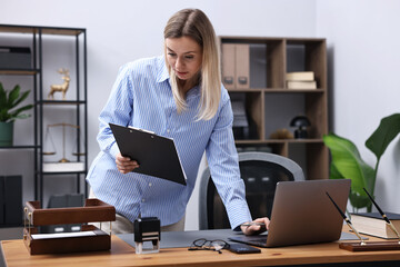 Notary with clipboard working at wooden desk in office