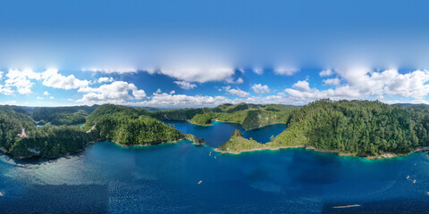 Aerial view of a turquoise lagoon surrounded by dense tropical vegetation. The irregular shape of the water forms small coves and tree-covered peninsulas, creating a striking contrast between the deep © Felipe